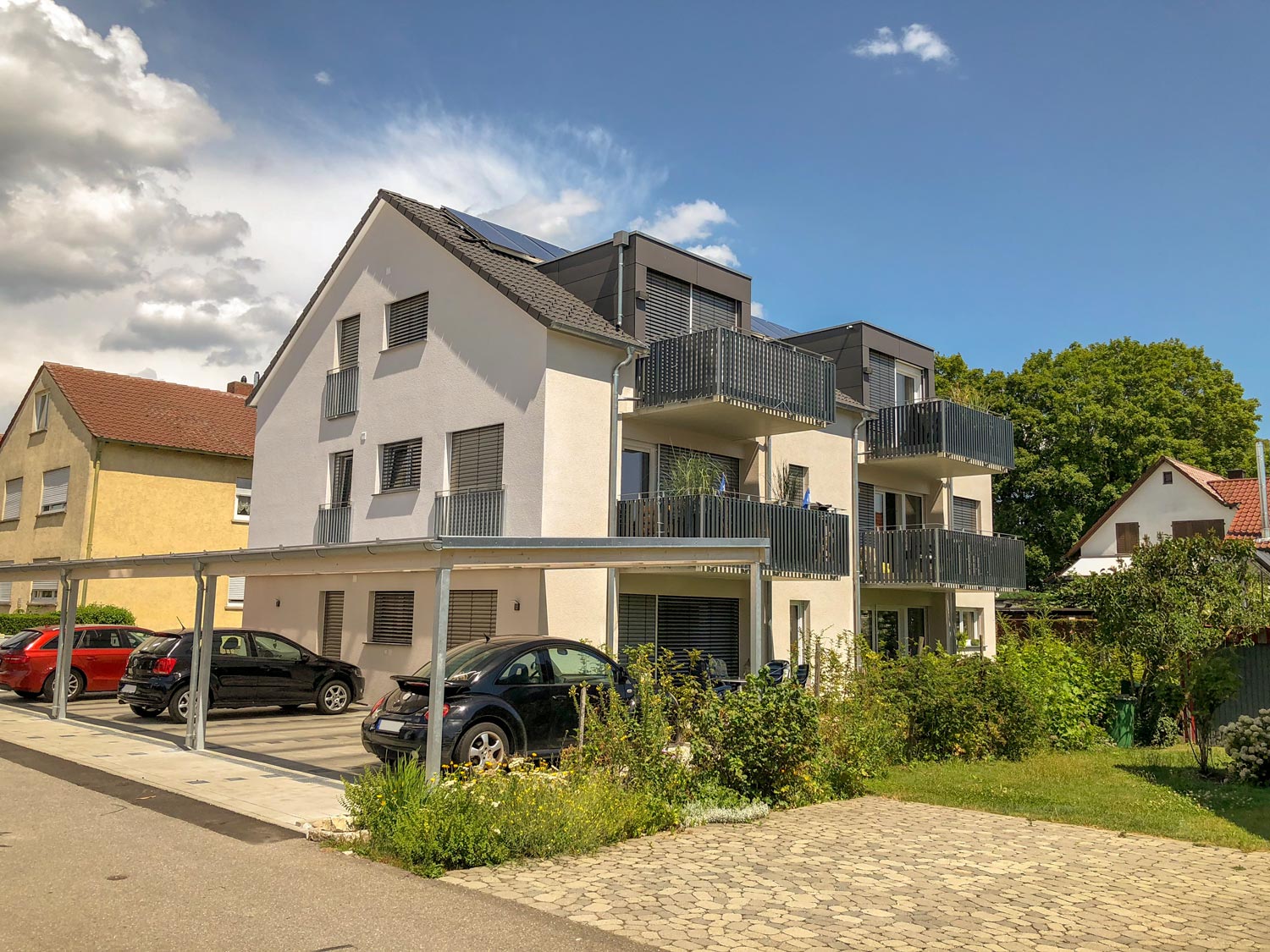 Neubau mit modernen Balkonen und Carport vor dem Gebäude, in einem ruhigen Wohnviertel von Ravensburg – perfekt zum Kauf eines Hauses.